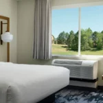 a guest room bed with a window view of trees at a Broomfield, CO hotel