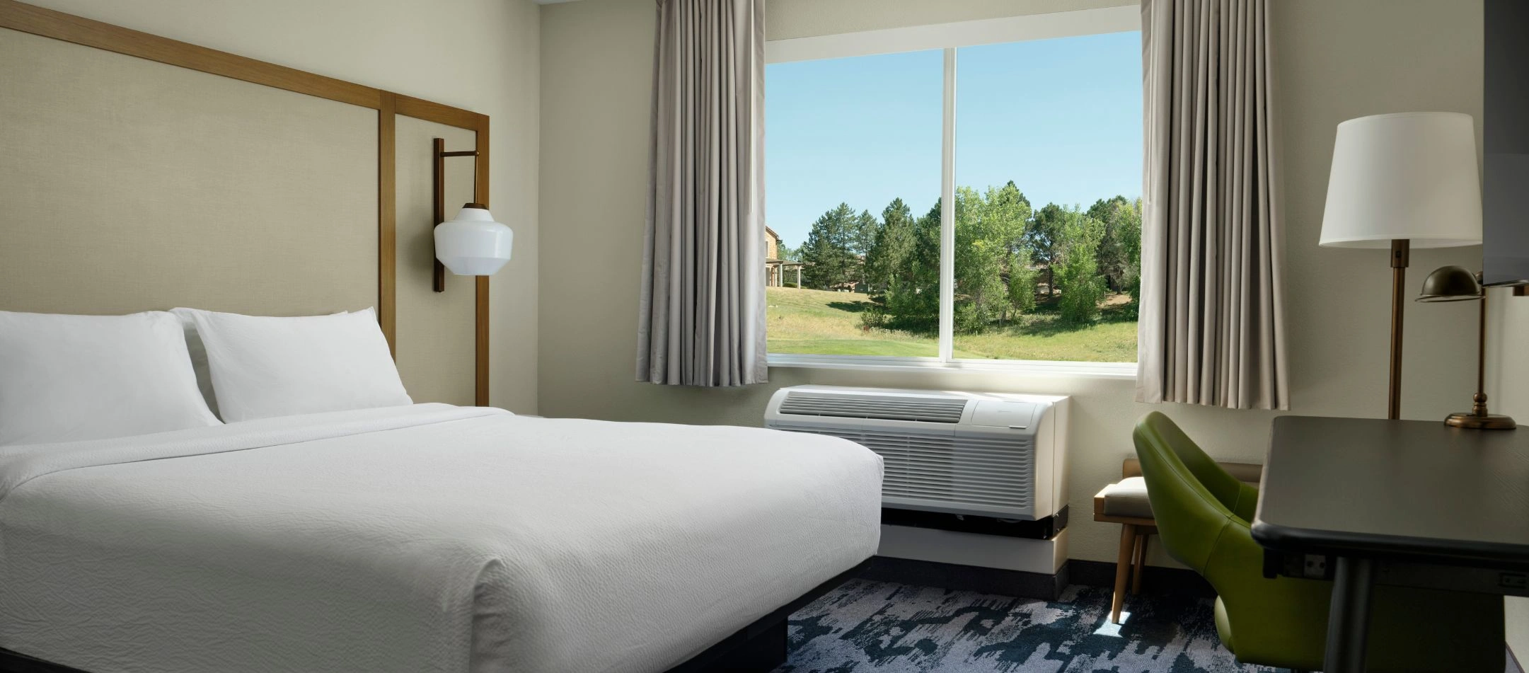 a guest room bed with a window view of trees at a Broomfield, CO hotel