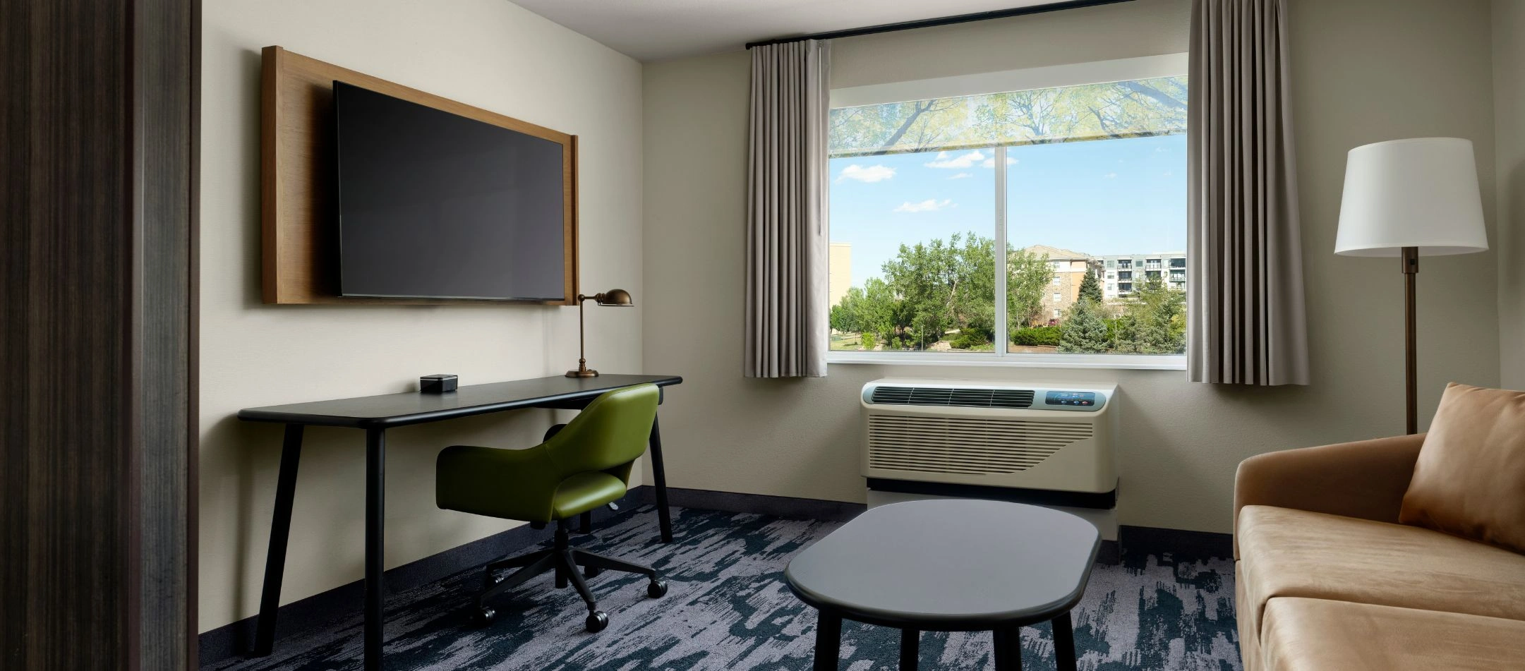 A hotel room lounge with a sofa and window view at a Broomfield, CO hotel