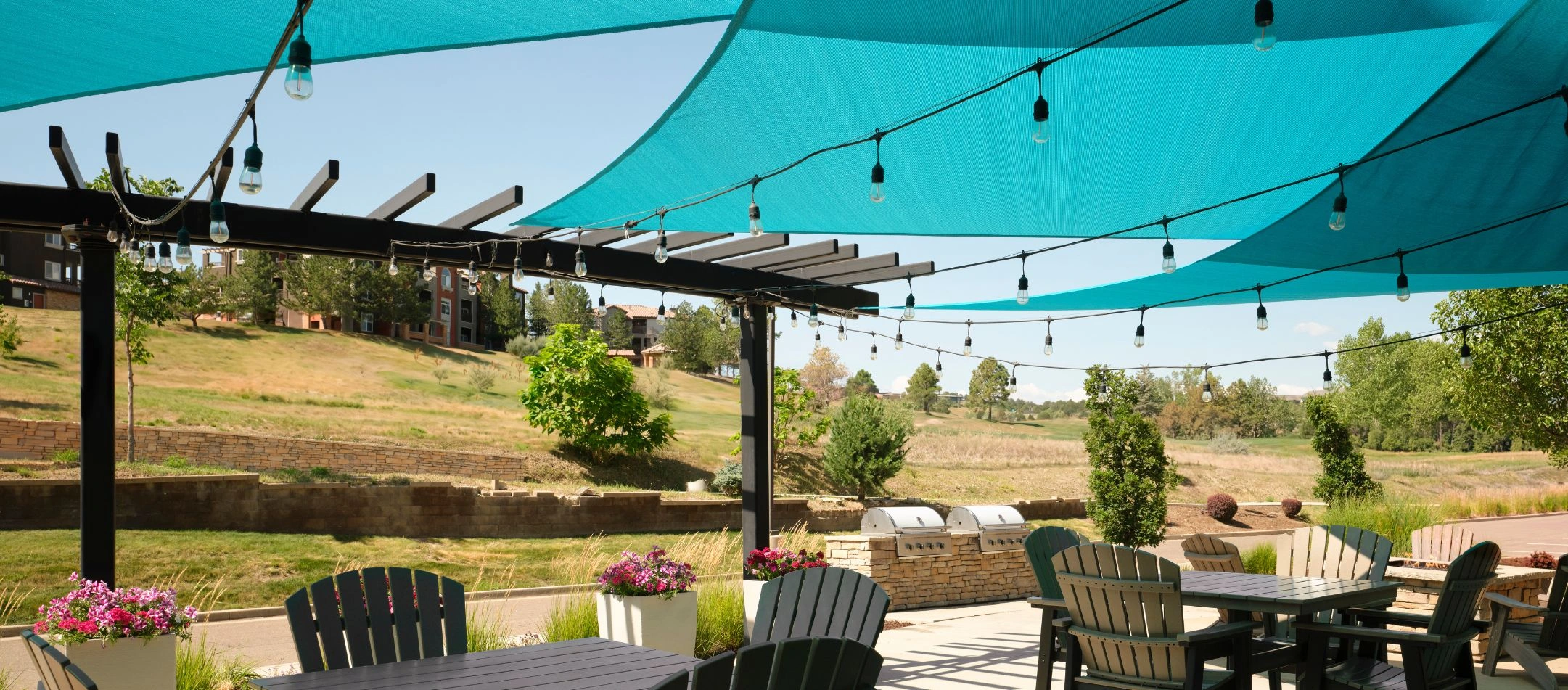 An outdoor patio with string lights and a shade sail at a Broomfield, CO hotel
