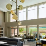 A dining area with globe pendant lights and window seating at a Broomfield, CO hotel