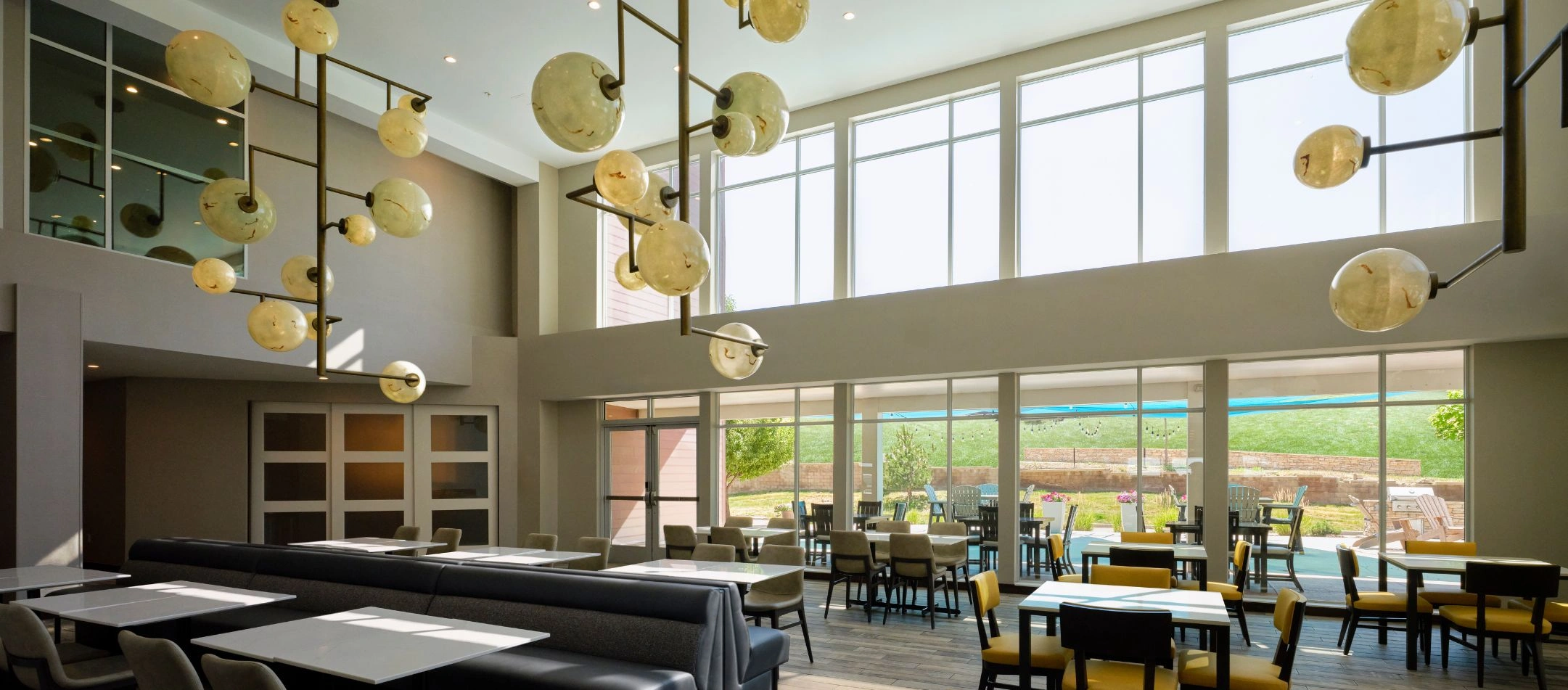 A dining area with globe pendant lights and window seating at a Broomfield, CO hotel