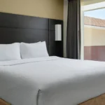 A bedroom with a dark wood headboard and window view at a Broomfield, CO hotel