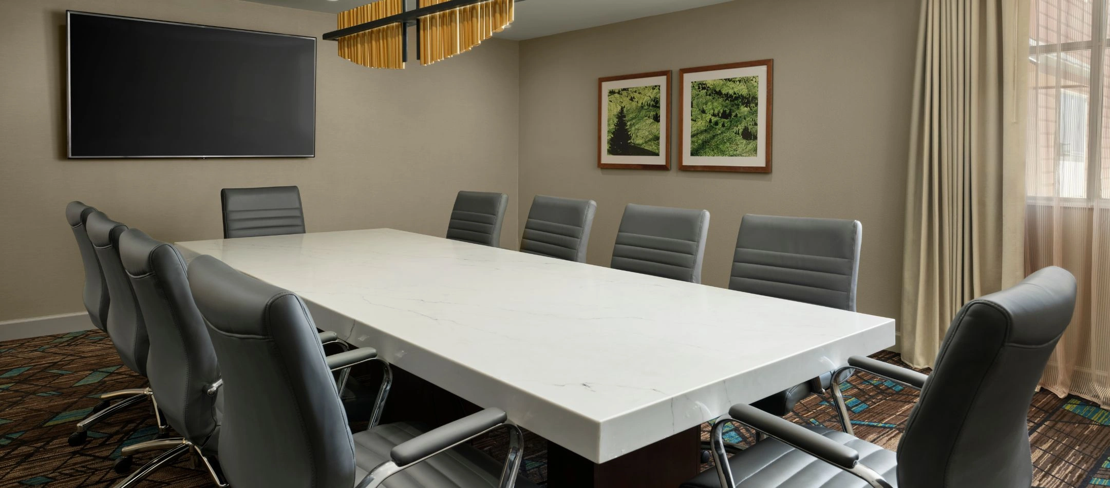 A boardroom with a marble table and gray leather chairs at a Broomfield, CO hotel