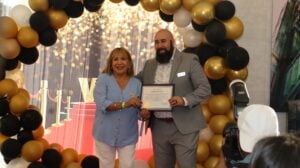 Two people holding an award and posing for a picture